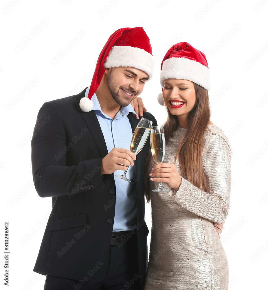 Happy couple in Santa Claus hats and with glasses of champagne on white background Happy couple in Santa Claus hats and with glasses of champagne on white background