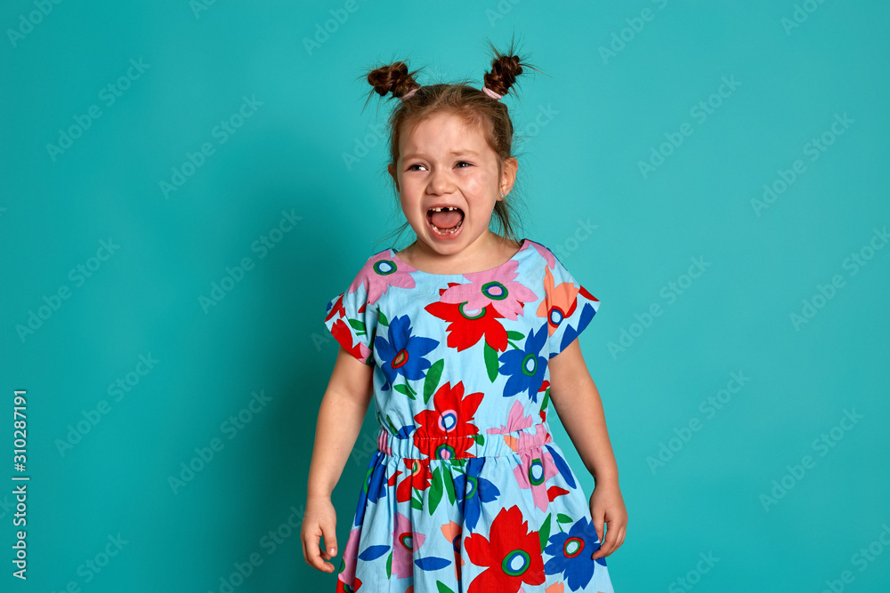 Little girl in on a blue background. Emotions of a child are anger, resentment, joy. Charming little girl smiling and showing her first lost milk tooth. Little girl in on a blue background. Emotions of a child are anger, resentment, joy. Charming little girl smiling and showing her first lost milk tooth.