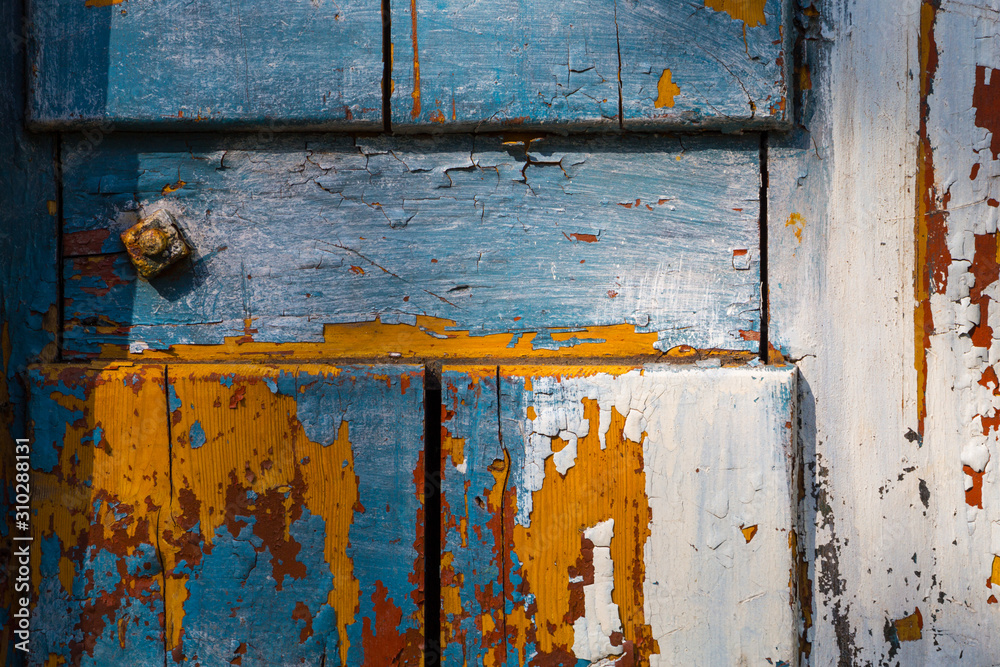 Vivid colors of layers of peeling paint on an old wooden board.