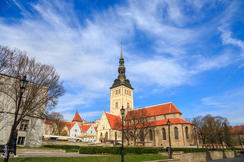 St. Nicholas' Church (Niguliste kirik) in Tallinn, Estonia, on a sunny day, under dramatic sky.