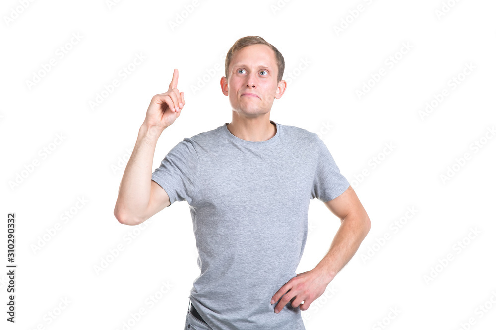 Young man points a finger up, standing on a white background. Young man points a finger up, standing on a white background.