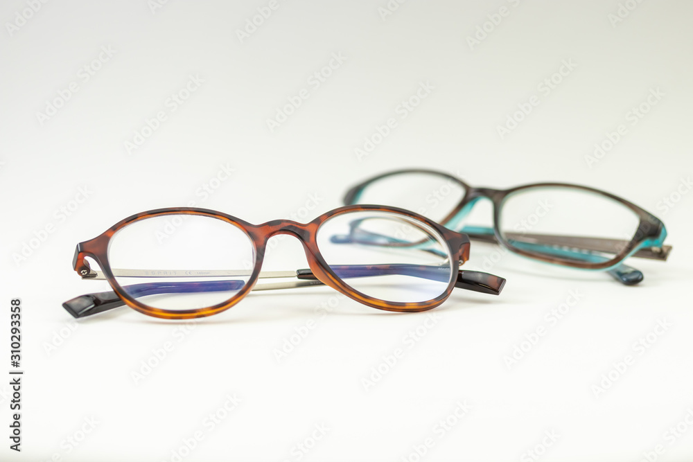 Two pairs of modern glasses isolated in a studio shot one with black and turquoise colored frames and a blue blocking pair prescribed from a profession optometrist with isolated white background Two pairs of modern glasses isolated in a studio shot one with black and turquoise colored frames and a blue blocking pair prescribed from a profession optometrist with isolated white background