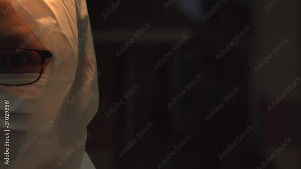 Asian woman scientist masked pan in dimly lit room