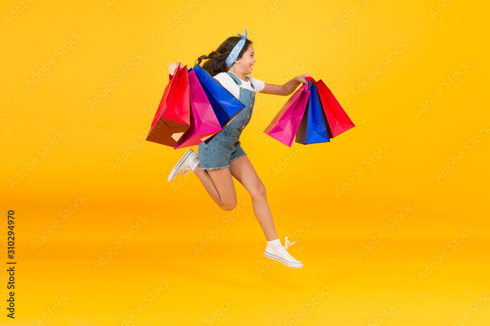 energetic child jump with heavy bags. holiday gifts in packages. cyber monday. hurry up its total sale. Kids fashion. Sales and discounts. happy small girl after successful shopping. Time to shop