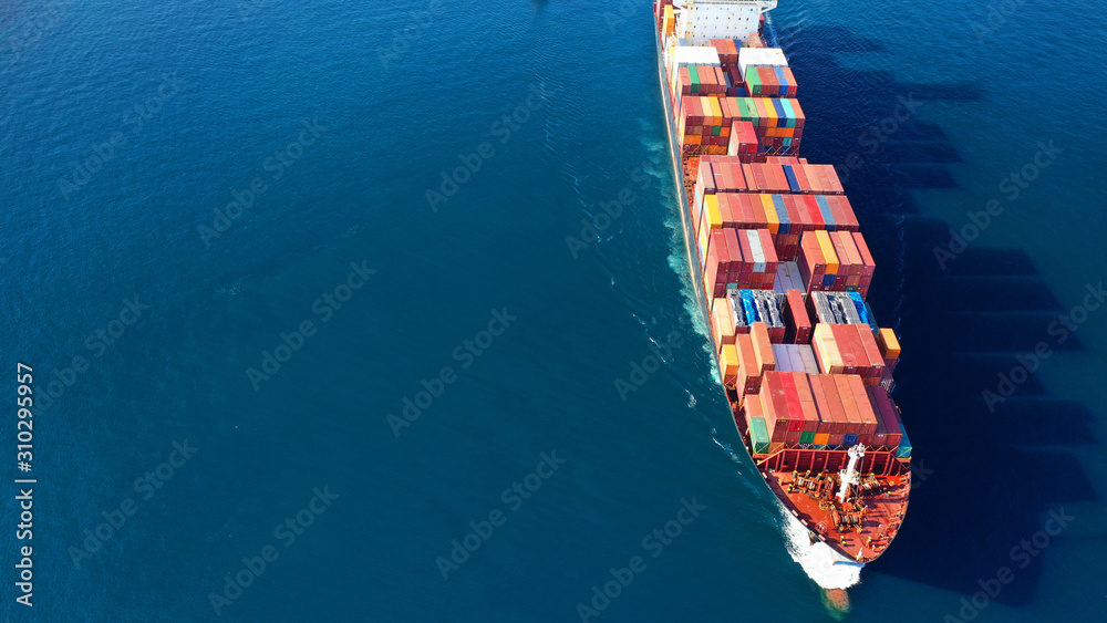 Fototapeta premium Aerial drone photo of industrial Cargo Container carrier tanker ship cruising Mediterranean open ocean deep blue sea helped by tug boat