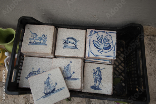 Light ceramic tiles with drawings of blue in Spain. Photography of beige stone stripes with a texture of chaotic lines with a blue ink pattern of animals, ships and leaves.