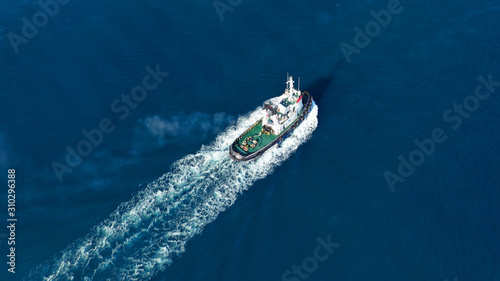 Aerial drone top down photo of tug boat cruising Mediterranean port