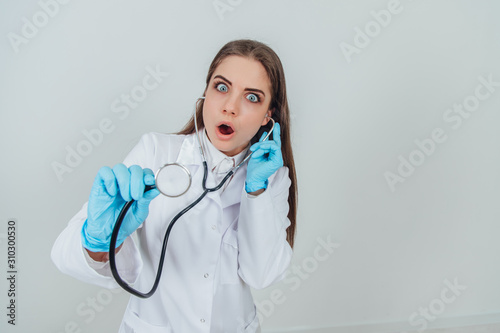 Attractive young doctor standing with stethoscope, terrified by what she has heard. Expressive face.