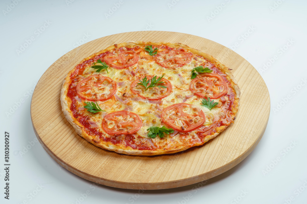 Pizza with slices of sausage, cheese and tomatoes, cut into rings. Pizza on a light wooden platter.  45 degree side view