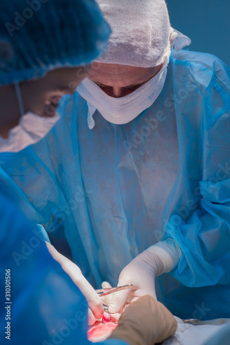 Children's surgeons perform urological surgery. A man and a woman in a mask, and a blue sterile gown, in the operating room.