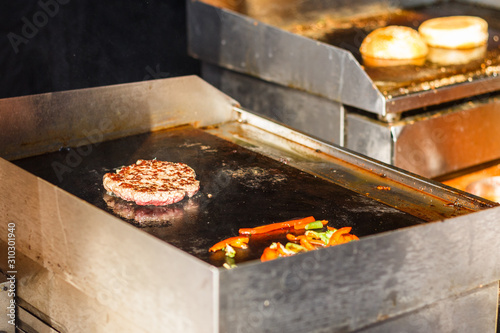 chef cooks burger at street food festival photo