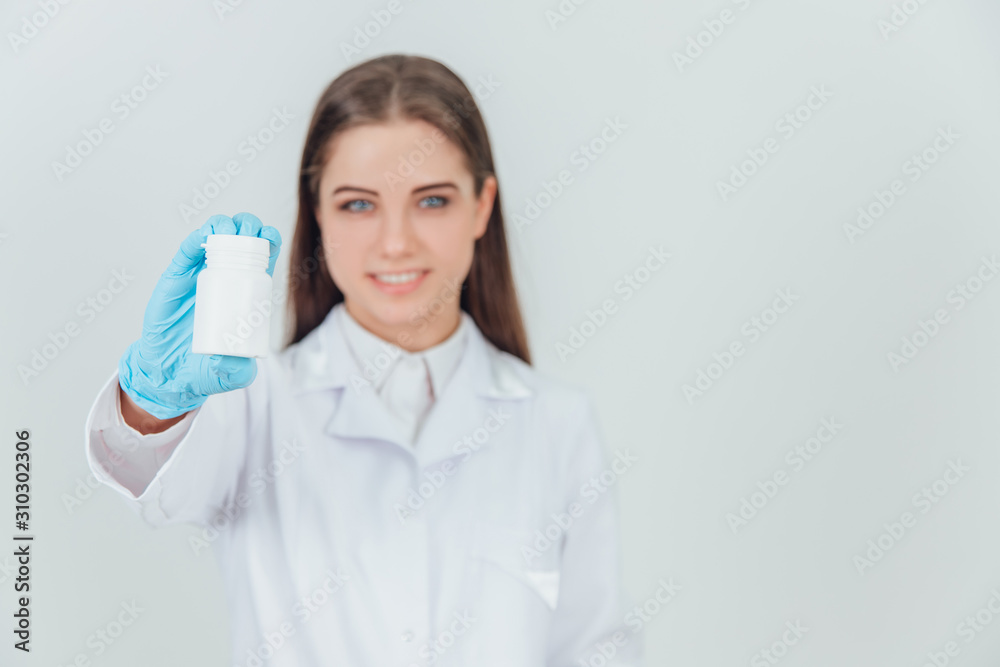 Blurred pretty smiling young intern girl holding a bottle of pills, extending it to the camera. Blurred pretty smiling young intern girl holding a bottle of pills, extending it to the camera.
