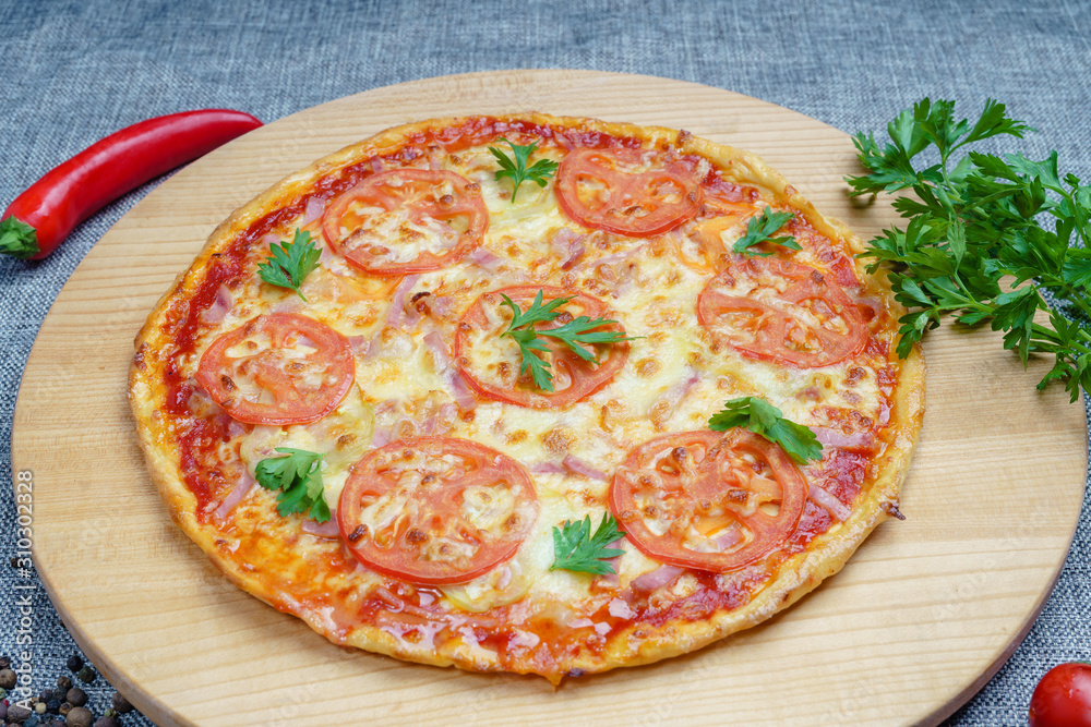 Pizza with slices of sausage, cheese and tomatoes, cut into rings. Pizza on a light wooden platter. 45 degree side view Pizza with slices of sausage, cheese and tomatoes, cut into rings. Pizza on a light wooden platter. 45 degree side view