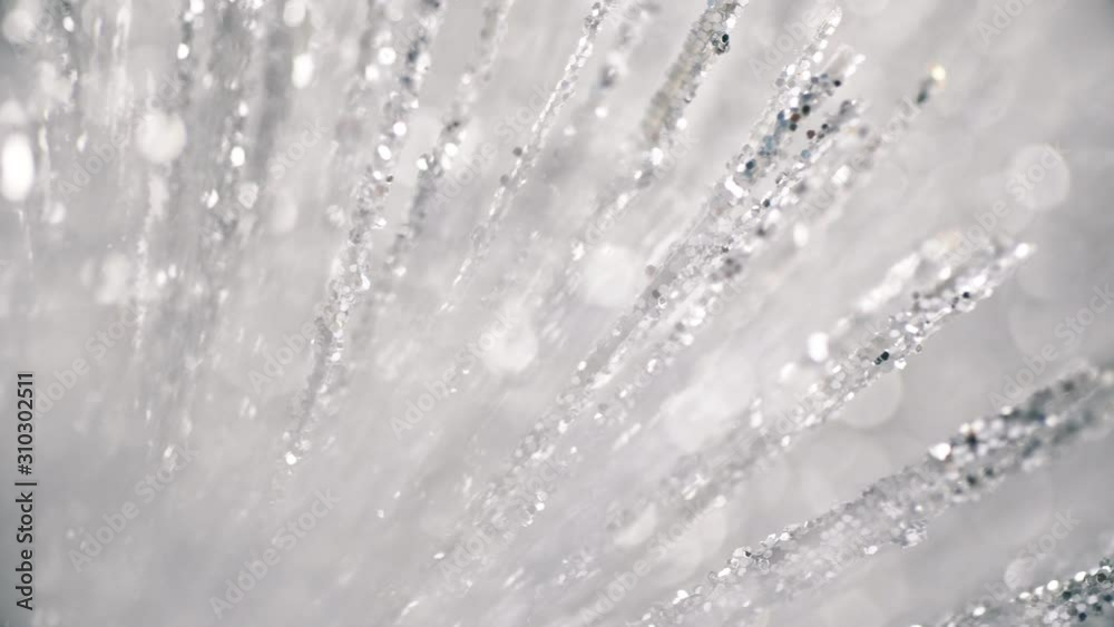 Silver tinsel glitter texture surface on black background. 4k close up macro of glittering material. Holiday abstract backdrop.