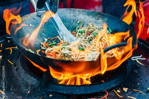 chef cooks Chinese noodle wok at street food festival