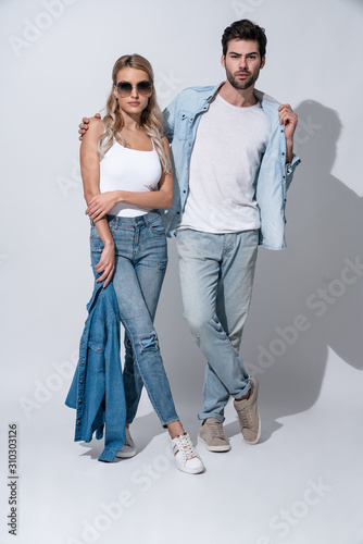 Stylish couple. Full length of beautiful young couple bonding while standing against grey background © Roman