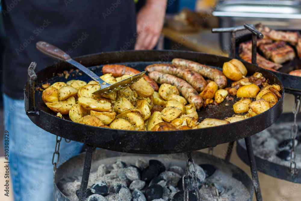 chef cooks potatoes and sausages at the street food festival chef cooks potatoes and sausages at the street food festival