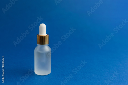 Cosmetic bottle with pipette on blue trendy background. Science or medical testing concept. Color of the year 2020