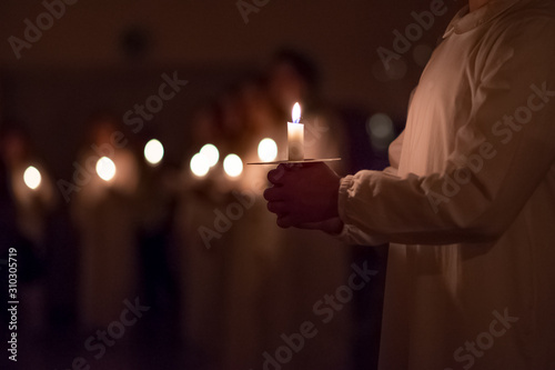 Boys are handling candles in the traditionall religious habit dresses in the church. Celebration of Lucia day in Sweden