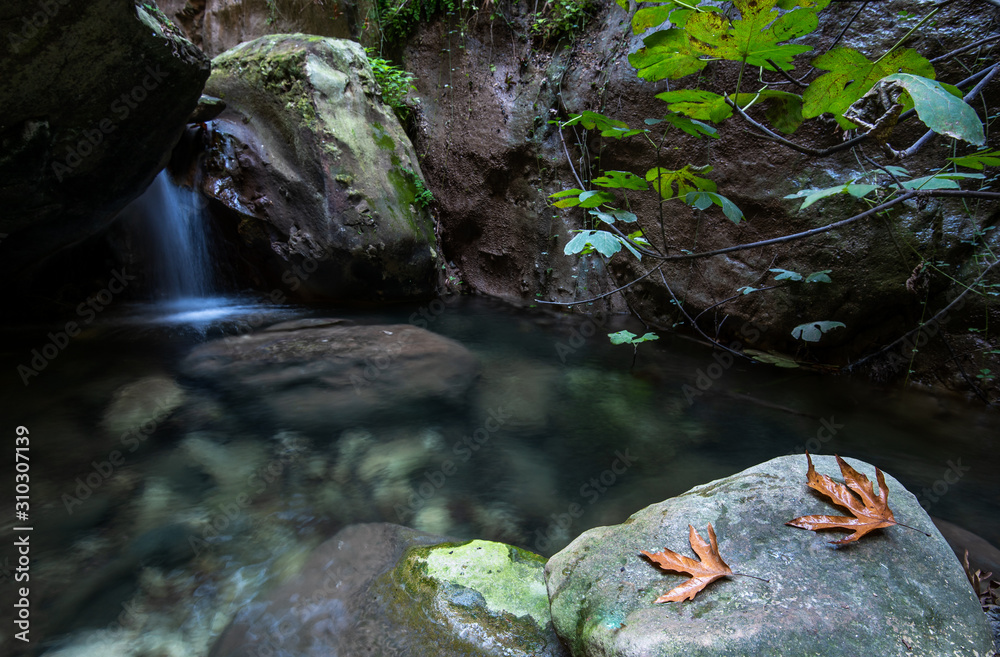 Fototapeta premium Idyllic calm lake with blue clean water and small waterfall flowing between the rocks.