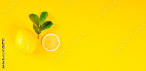 Lemons and green leaves on bright yellow background. Lemon background concept, flat lay. Lemon fruit, citrus minimal concept. Creative background made of lemon and leaf. Top View.