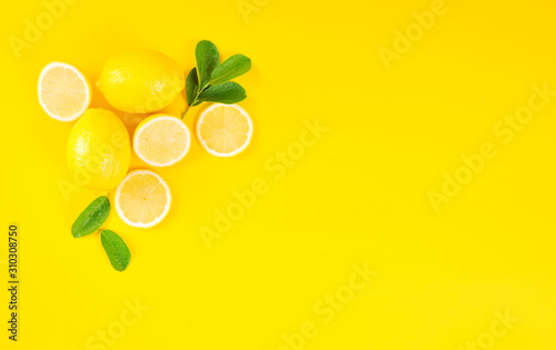 Lemons and green leaves on bright yellow background. Lemon background concept, flat lay. Lemon fruit, citrus minimal concept. Creative background made of lemon and leaf. Top View, copy space.
