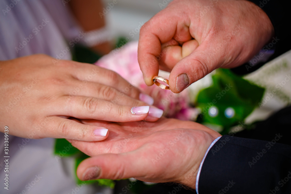 Groom putting wedding ring on bride's finger during the wedding ceremony 