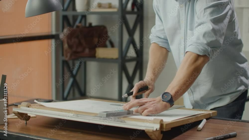 Architect man sits at drafting table in modern industrial office during the day Architect man sits at drafting table in modern industrial office during the day