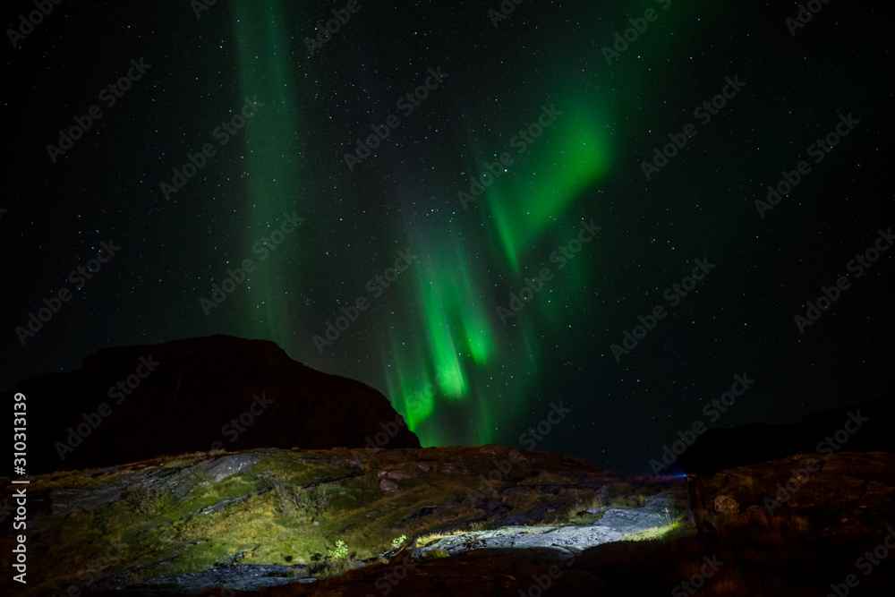 Man with flashlight and northern lights on sky