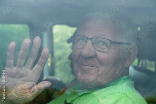 Wallpaper Mural Lächelnder Senior winkt in einem Auto hinter einer Scheibe Torontodigital.ca