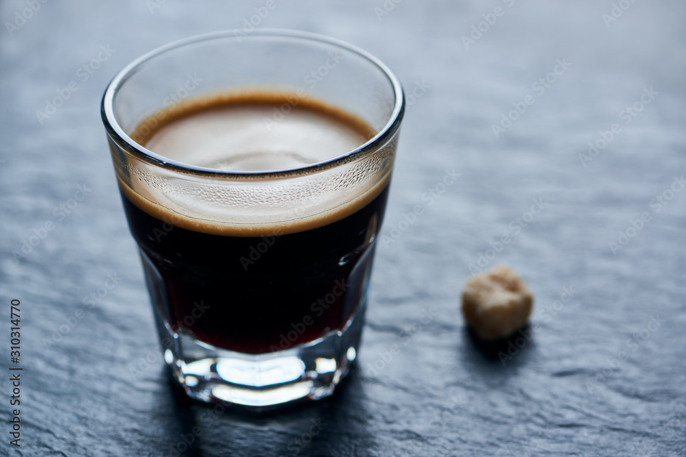 Coffee in glass cup on dark stone background. Close up. Coffee in glass cup on dark stone background. Close up.