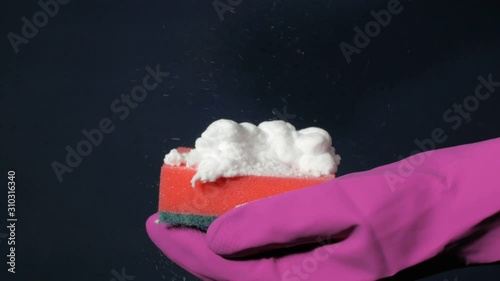 Sponge in male hand in magenta rubber glove. White foam splashes out of the spray can. photo