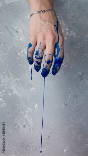 Elegant female hand on in dark blue paint, on a gray textured background
