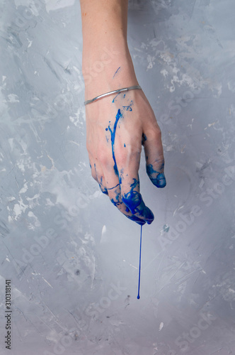 Elegant female hand on in dark blue paint, on a gray textured background