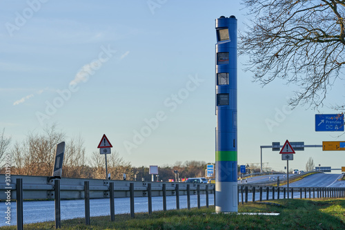 germany, road toll, blue pillar, truck toll station on green gras, traffic signs in the background, blue sky, winter sun, toll collect, maut