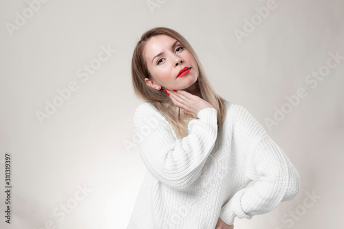 Woman with red lips and nails surprise holds cheeks by hand .Beautiful girl with curly hair surprised and shocked looks on you . Presenting your product. Expressive facial expressions.