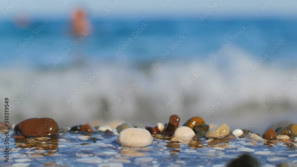 Static shot of seacoast of Turkey, close up of multi color pebble, defocused sea waves in background