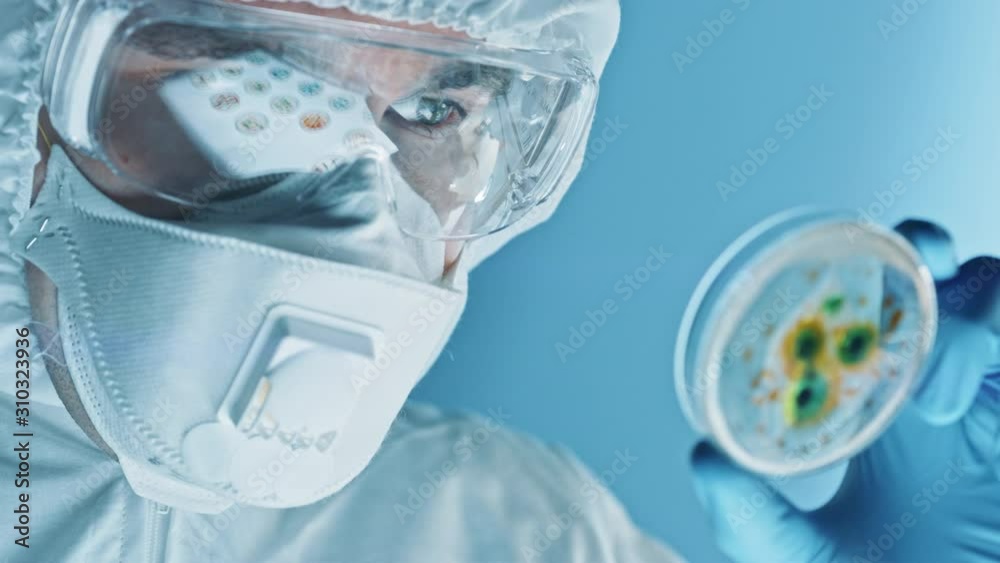 Scientist Wearing Respirator Mask, Coverall and Safety Glasses Looks at