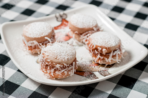4 Latin American alfajores with arequipe and coconut on plaid background