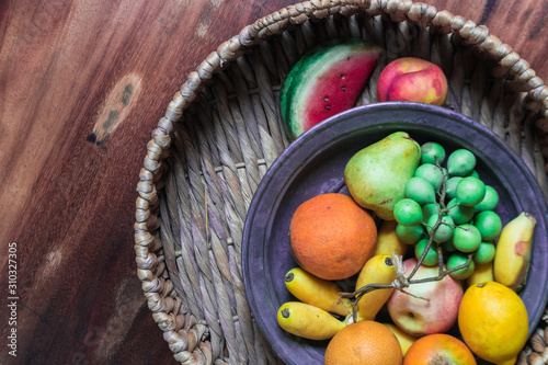 Fruit basket bottom that includes watermelon, bananas, grapes, granadilla, apples