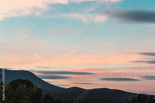 sunset sky over the hills in Tasmania, Australia with soft tones and trees