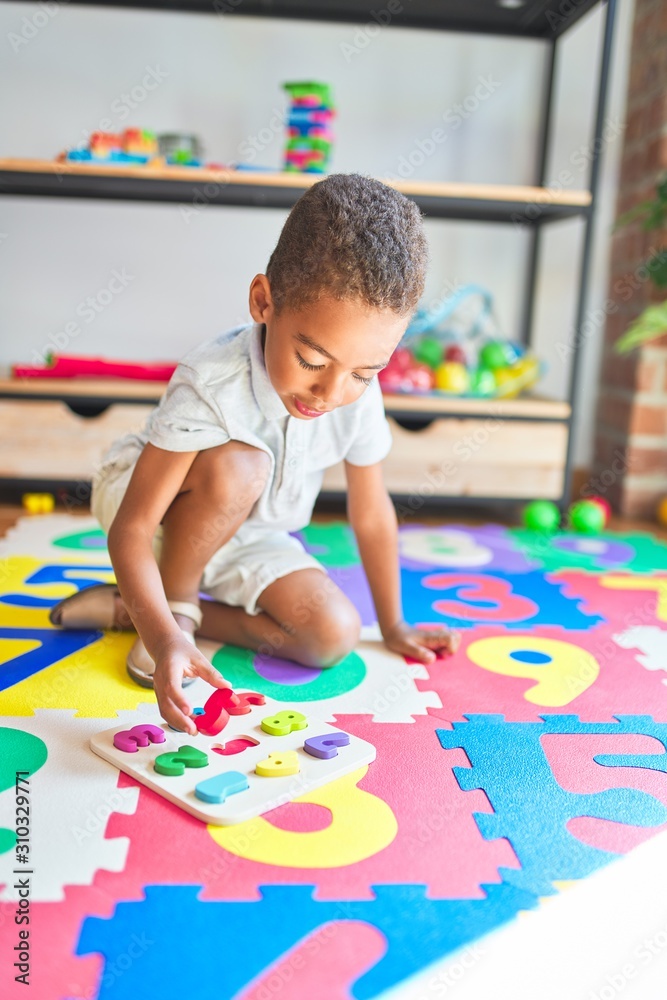Fototapeta premium Beautiful african american toddler playing with maths game using numbers at kindergarten
