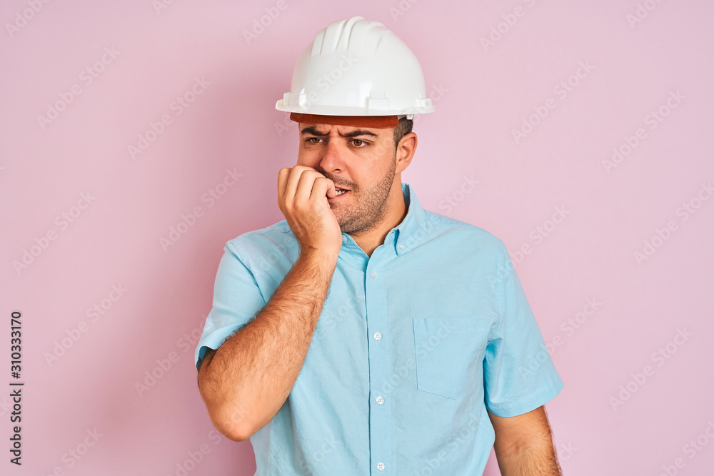 Young architect man wearing security helmet standing over isolated pink background looking stressed and nervous with hands on mouth biting nails. Anxiety problem. Young architect man wearing security helmet standing over isolated pink background looking stressed and nervous with hands on mouth biting nails. Anxiety problem.