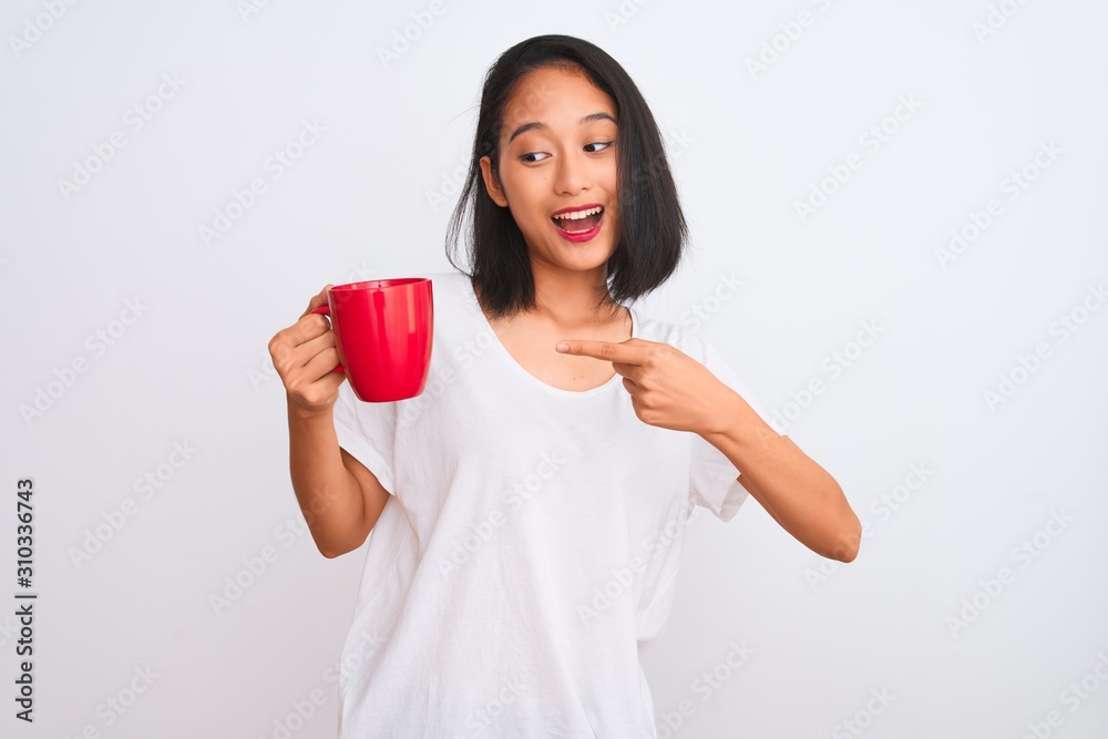 Young beautiful chinese woman drinking cup of coffee over isolated white background very happy pointing with hand and finger Young beautiful chinese woman drinking cup of coffee over isolated white background very happy pointing with hand and finger
