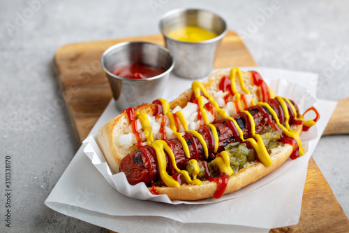 Fotografia, Obraz Classic american beef hot dog topped with ketchup, mustard, relish and onion
