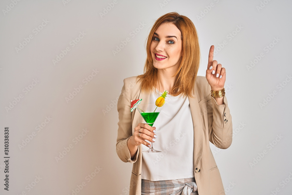 Redhead caucasian business woman drinking a summer cocktail over isolated background surprised with an idea or question pointing finger with happy face, number one