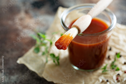 Homemade sweet and spicy barbeque sauce with a basting brush in a jar