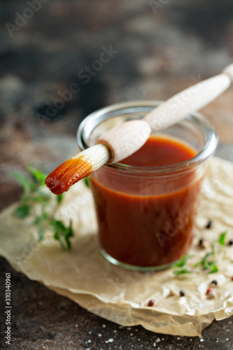 Homemade sweet and spicy barbeque sauce with a basting brush in a jar
