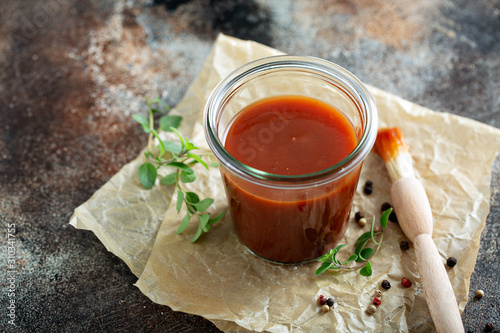 Homemade sweet and spicy barbeque sauce with a basting brush in a jar