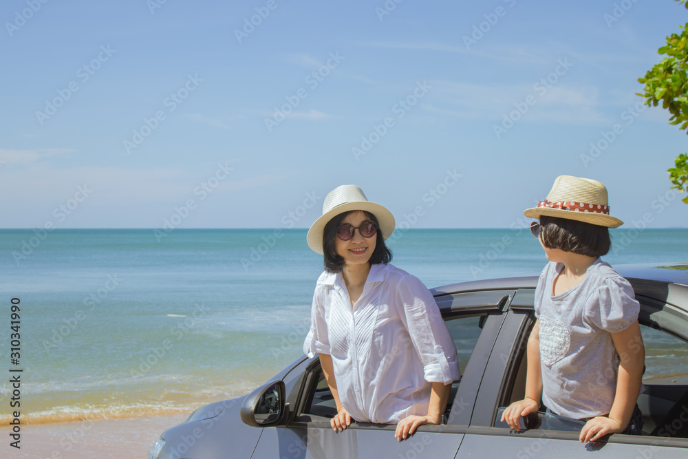 Summer Vacation and Car Trip Concept : Family car trip at the sea, Woman and child cheerful in car with seascape in the background, They feeling happiness.